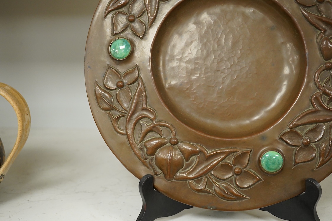 An Arts and Crafts embossed copper dish, in the manner of John Pearson, inlaid with Ruskin cabochons, unsigned, 32cm in diameter